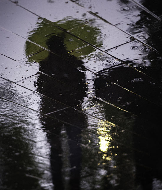 تصویری از رفلکس مردی با چتر در باران با مفهوم انتزاعی امنیت شغلی